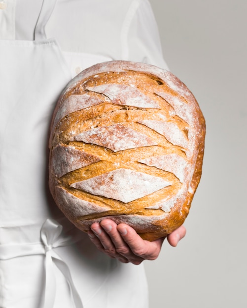 Front view chef wearing white clothes holding a bread