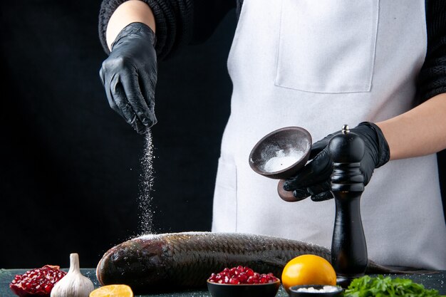 テーブルの上のボウルの新鮮な魚ザクロの種子に手袋をはめて塩を振りかけた正面図のシェフ