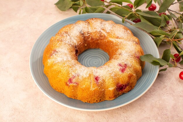 A front view cherry cake round formed inside blue plate on the pink desk