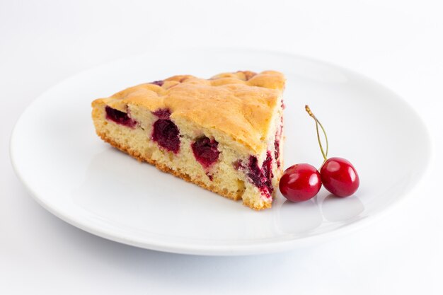 Front view of cherry cake slice inside white plate on the white surface