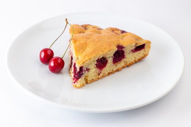 Front view of cherry cake slice inside white plate on the white surface