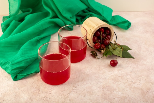 A front view cherry cocktail red inside little glasses fresh cooling along with fresh cherries on pink