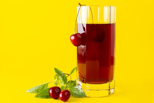 Front view of cherry juice inside long glass on the yellow surface