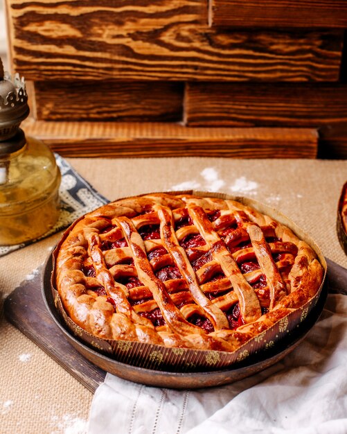 Вид спереди вишневого пирога внутри круглой сковороды на светлом полу