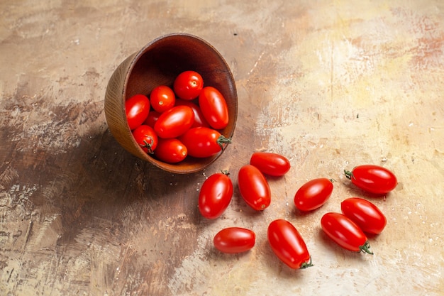 Front view cherry tomatoes scattered from bowl on amber background free space