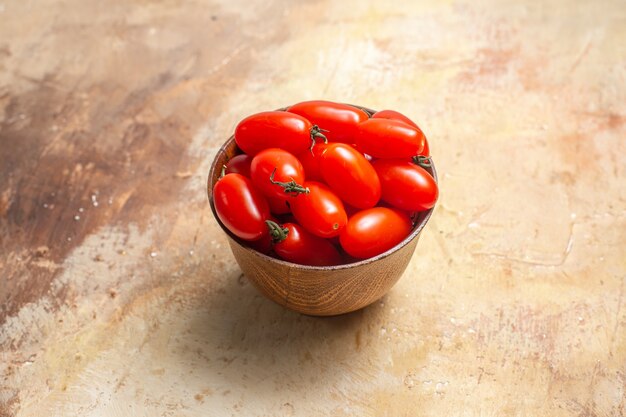 Front view cherry tomatoes in wooden bowl on amber background with free space