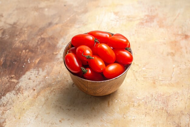 Front view cherry tomatoes in wooden bowl on amber with free space