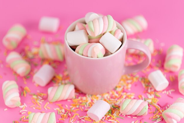 A front view chewing marshmallows inside pink, cup and all on pink, color rainbow sugar confiture