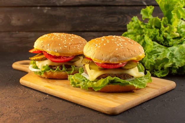 Куриный бургер с сыром и зеленым салатом на деревянном столе и бутерброд фаст-фуд, вид спереди