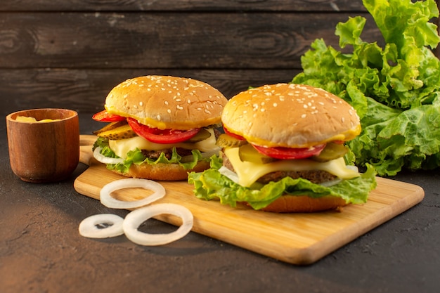 Куриный бургер с сыром и зеленым салатом на деревянном столе и бутерброд фаст-фуд, вид спереди