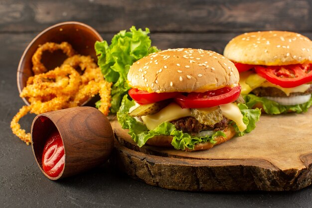 A front view chicken burgers with cheese and green salad on the wooden desk and sandwich fast-food meal food