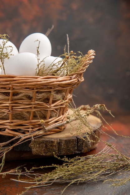 Front view chicken eggs inside basket on the dark surface