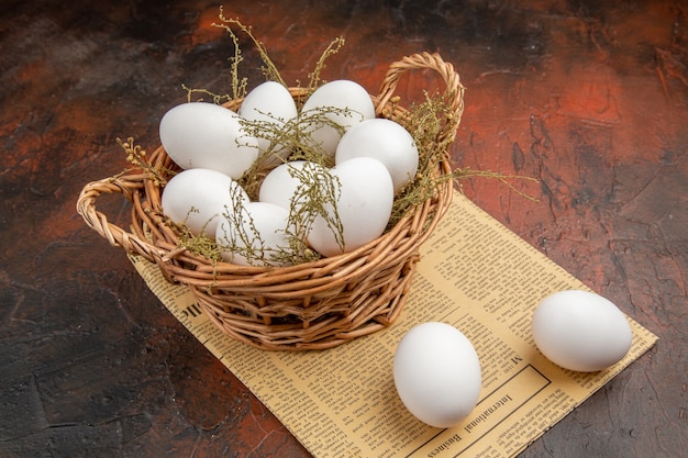 Front view chicken eggs inside basket on the dark surface