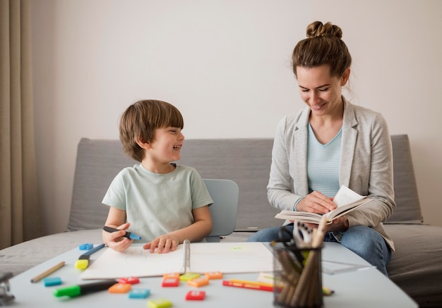 Front view of child being tutored at home by woman