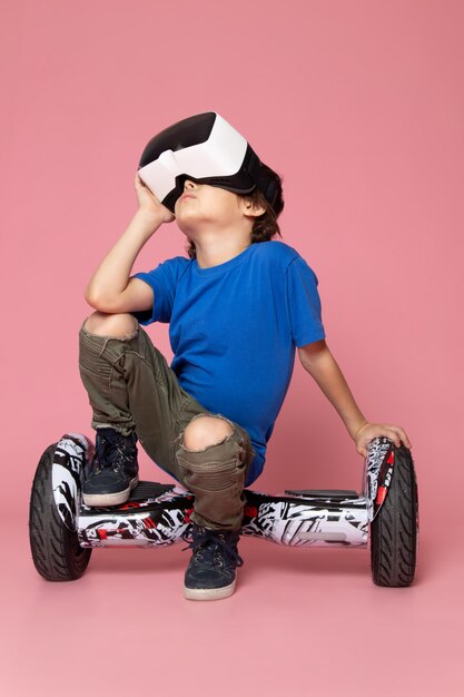 분홍색 공간에 세그웨이에 VR을 재생하는 파란색 티셔츠에 전면보기 아이 소년