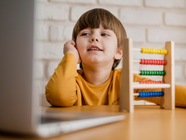 Front view of child at desk with laptop and abacus