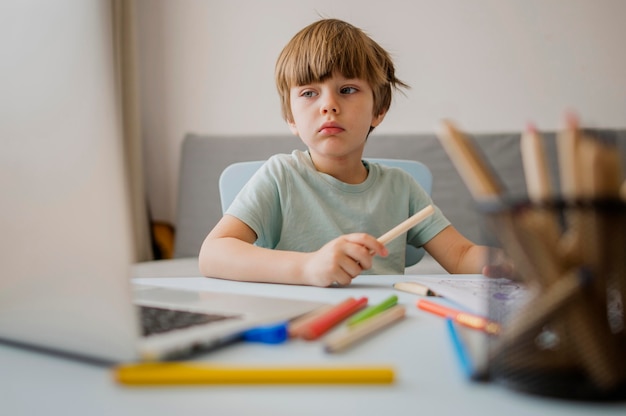 Free photo front view of child at home learning form laptop