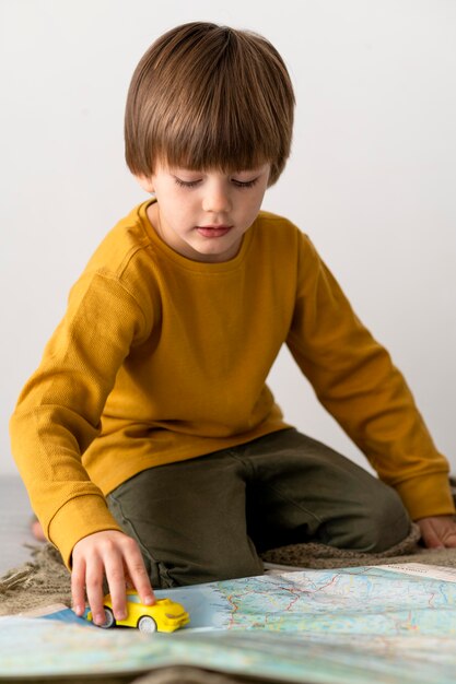 Front view of child playing with toy car on map