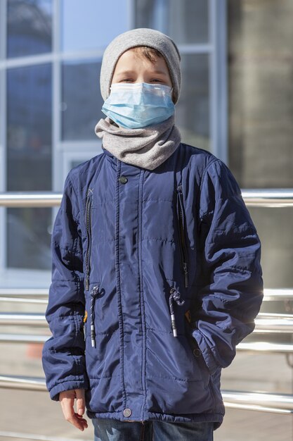 Front view of child wearing medical mask outside