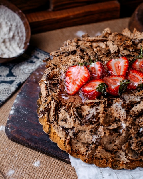 Вид спереди шоколадный торт вкусный сладкий с красной клубникой сверху на коричневом полу