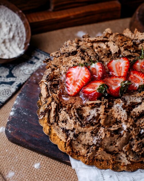 Front view choco cake tasty sweet with red strawberries on top on the brown floor