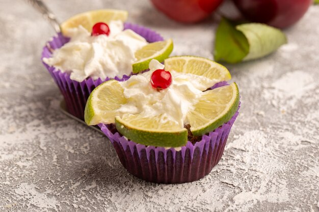 Front view of chocolate brownies with cream and lemon slices along with plums