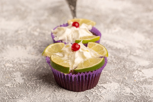 Front view of chocolate brownies with cream and lemon slices on the white surface