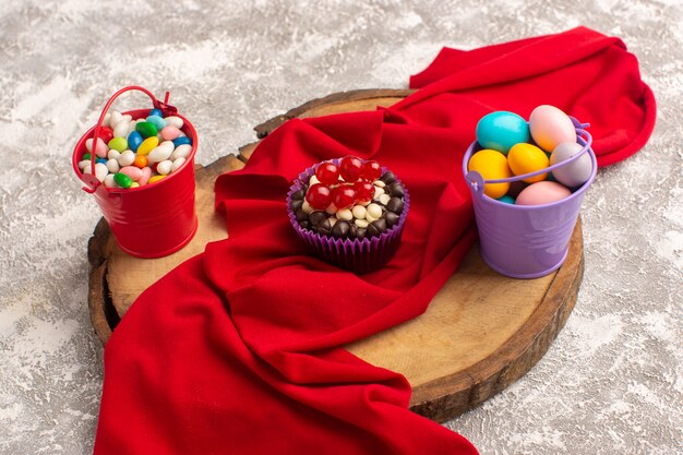 Front view of chocolate brownies with different candies on the light surface