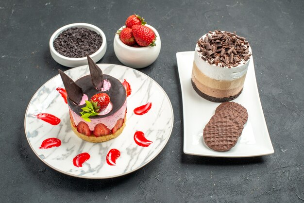 전면 보기 초콜릿 케이크와 흰색 직사각형 접시에 비스킷 흰색에 딸기 치즈 케이크