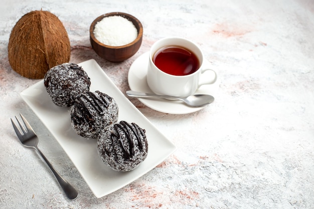 Torte al cioccolato di vista frontale con la tazza di tè sui biscotti dolci dello zucchero del biscotto della torta di cioccolato dello scrittorio bianco