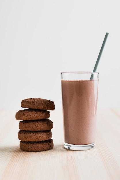 Front view chocolate milk in glass with straw and cookies