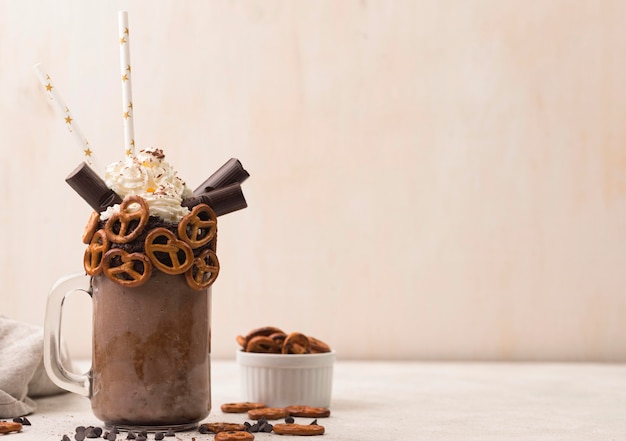 Front view of chocolate milkshake glass with pretzels and copy space