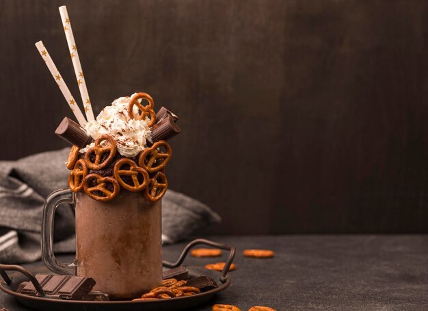 Front view of chocolate milkshake with straws and pretzels
