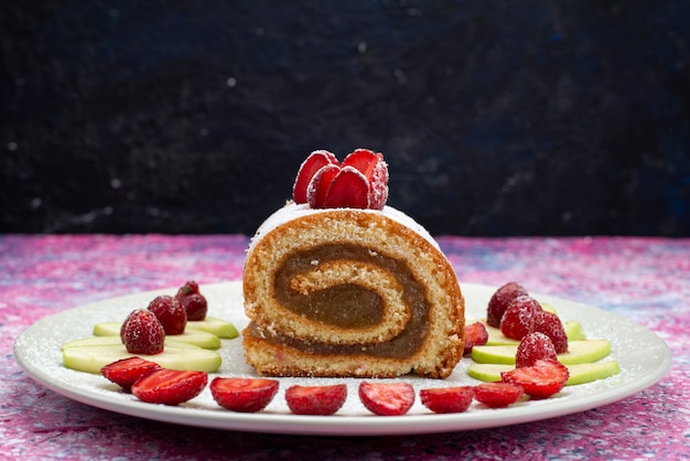 Front view of chocolate roll cake with strawberries and apples on the dark desk