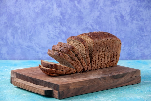 Front view of chopped in half black bread slices on wooden boards on light ice blue pattern background