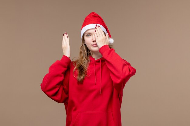 茶色の背景モデルの休日のクリスマスに彼女の顔を覆う正面のクリスマスの女の子