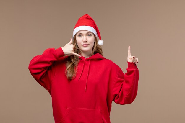 正面図のクリスマスの女の子が茶色の背景の女性の休日のクリスマスにポーズをとる