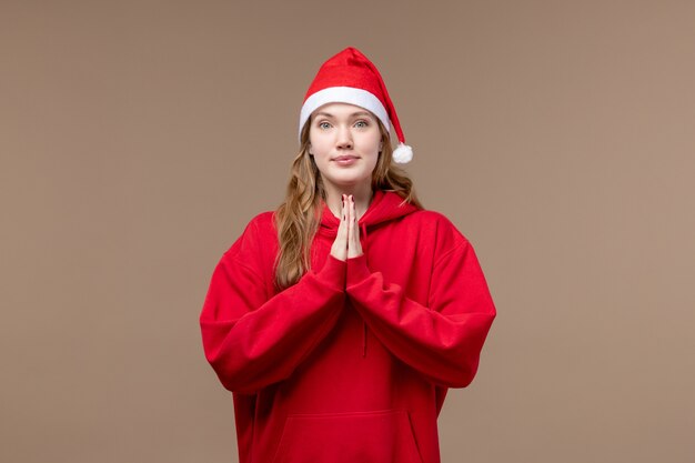 茶色の背景の休日のモデルのクリスマスに祈る正面のクリスマスの女の子