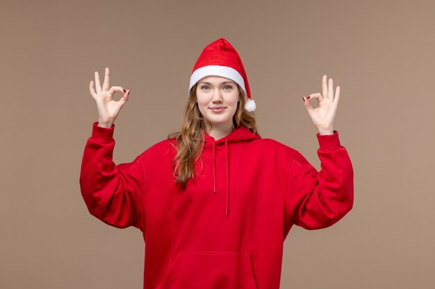 正面図のクリスマスの女の子が茶色の背景モデルの休日のクリスマスに笑って