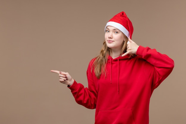 正面図のクリスマスの女の子が茶色の背景に笑っている女性の休日のクリスマスの感情