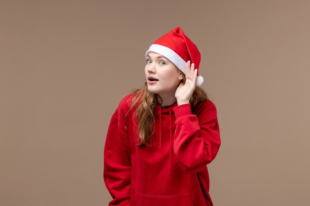 Front view christmas girl trying to listen closely on brown background holiday christmas emotion