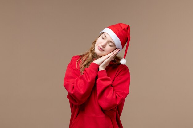 Вид спереди рождественская девушка пытается заснуть на коричневом фоне праздник рождественские эмоции