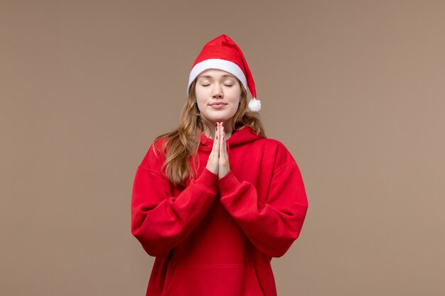 Front view christmas girl with praying expression on a brown space