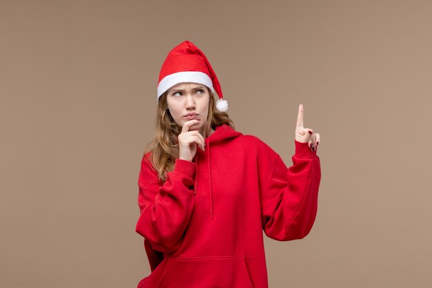 Вид спереди рождественская девушка с выражением мышления на коричневом фоне женщина праздник рождество