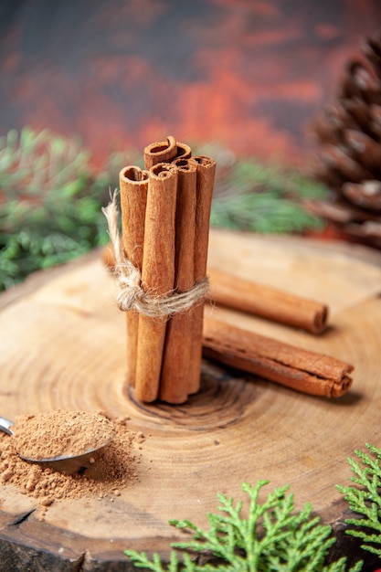 Front view cinnamon sticks cinnamon powders pinecone on wood board on dark