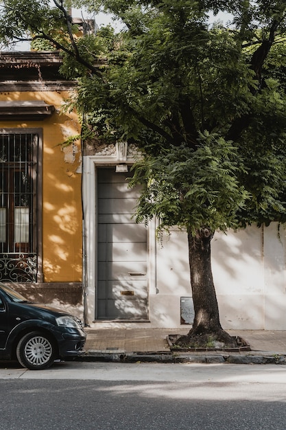 Foto gratuita vista frontale della casa di città con auto e albero