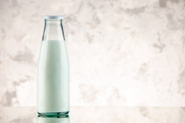 Front view of closed and filled with milk glass bottle on the right side on white smoke background with free space