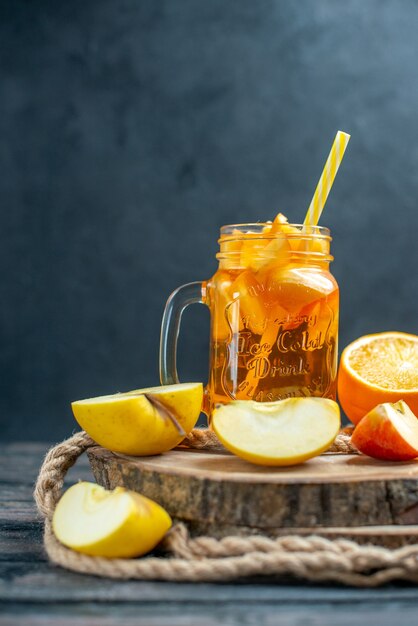 Front view cocktail cut oranges and apples on wood board on dark isolated background