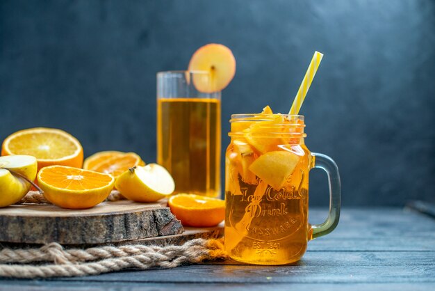 Front view cocktail cut oranges and apples on wood board on dark isolated background