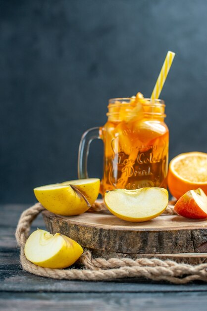 Front view cocktail cut oranges and apples on wood board on dark isolated background